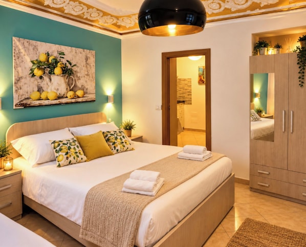 Una cama bien hecha con una decoración en blanco y beige, un cuadro de limones en la pared y un armario de madera.
