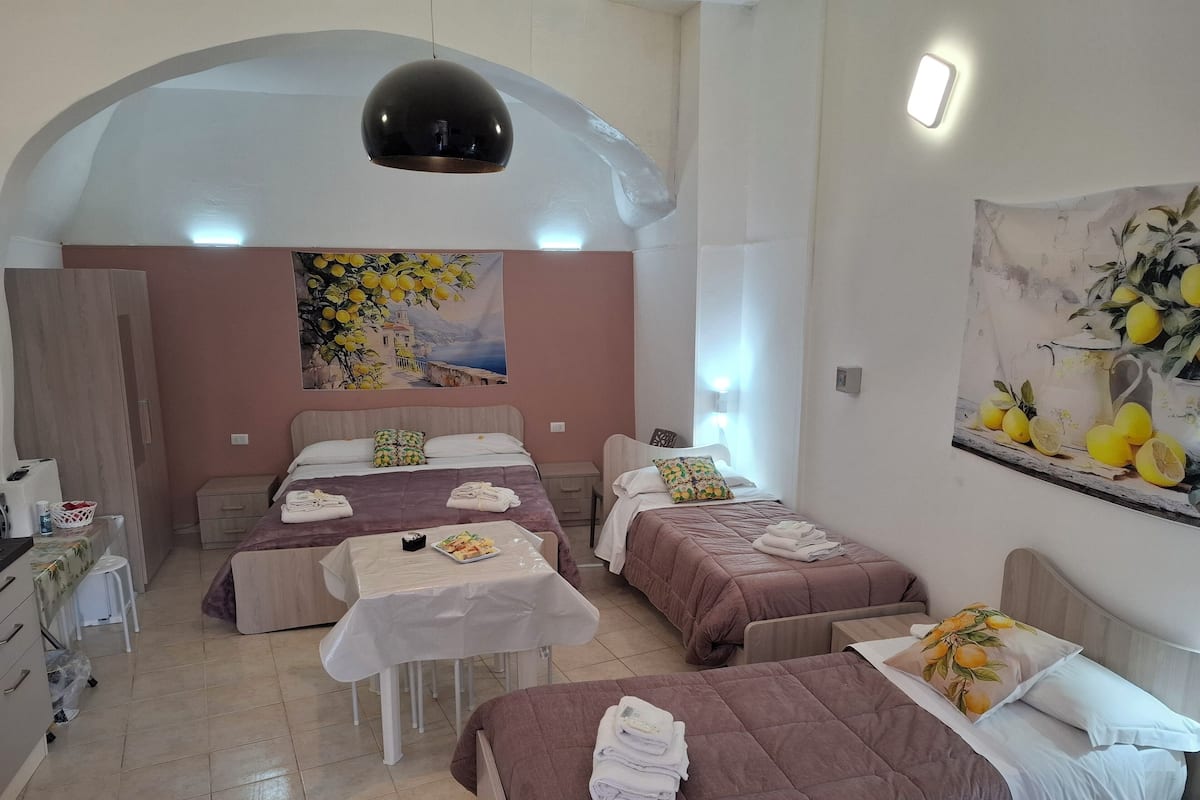 Ein Hotelzimmer mit zwei Betten, einem Esstisch und einer Küchenzeile.