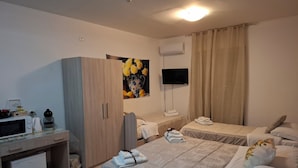 Ein Hotelzimmer mit zwei Betten, einem Schreibtisch, einer Mikrowelle, einem Fernseher und einer kleinen Kühlbox.