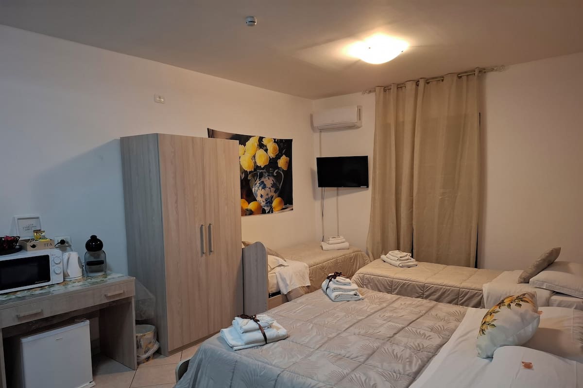Ein Hotelzimmer mit zwei Betten, einem Schreibtisch, einer Mikrowelle, einem Fernseher und einer kleinen Kühlbox.