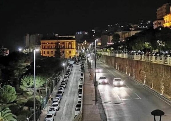 Une rue de la ville de nuit, avec des voitures garées, des lampadaires et des immeubles.