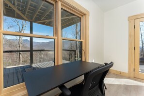 A room with a large window, a desk, and a chair.