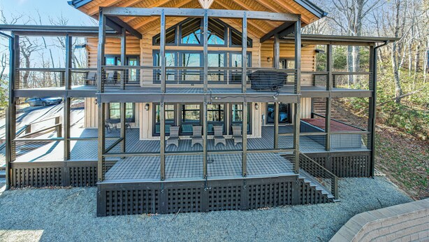 Eine mehrstöckige Holz-Blockhütte mit Balkon, großen Fenstern und Metallgeländer.