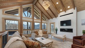 Ein geräumiges Wohnzimmer mit hohen Decken, großen Fenstern und einem Kamin.