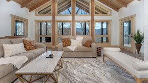 Ein geräumiges Wohnzimmer mit hohen Decken, großen Fenstern und einer gemütlichen Sitzecke.