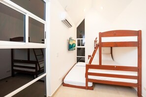 Ein kleines Zimmer mit Stockbetten, einem kleinen Schreibtisch und einem Fenster.