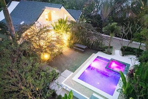 A residential property with a swimming pool, a well-maintained garden, and a house with a sloped roof.