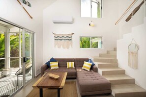 A modern interior with a sectional sofa, a wooden table, and a staircase.