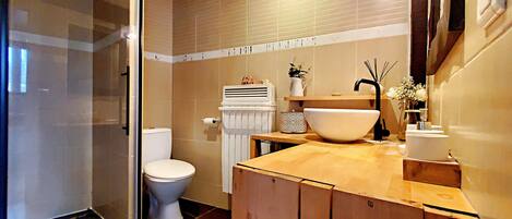 A modern bathroom with a glass shower enclosure, a toilet, a sink with a large basin, and a towel rack.