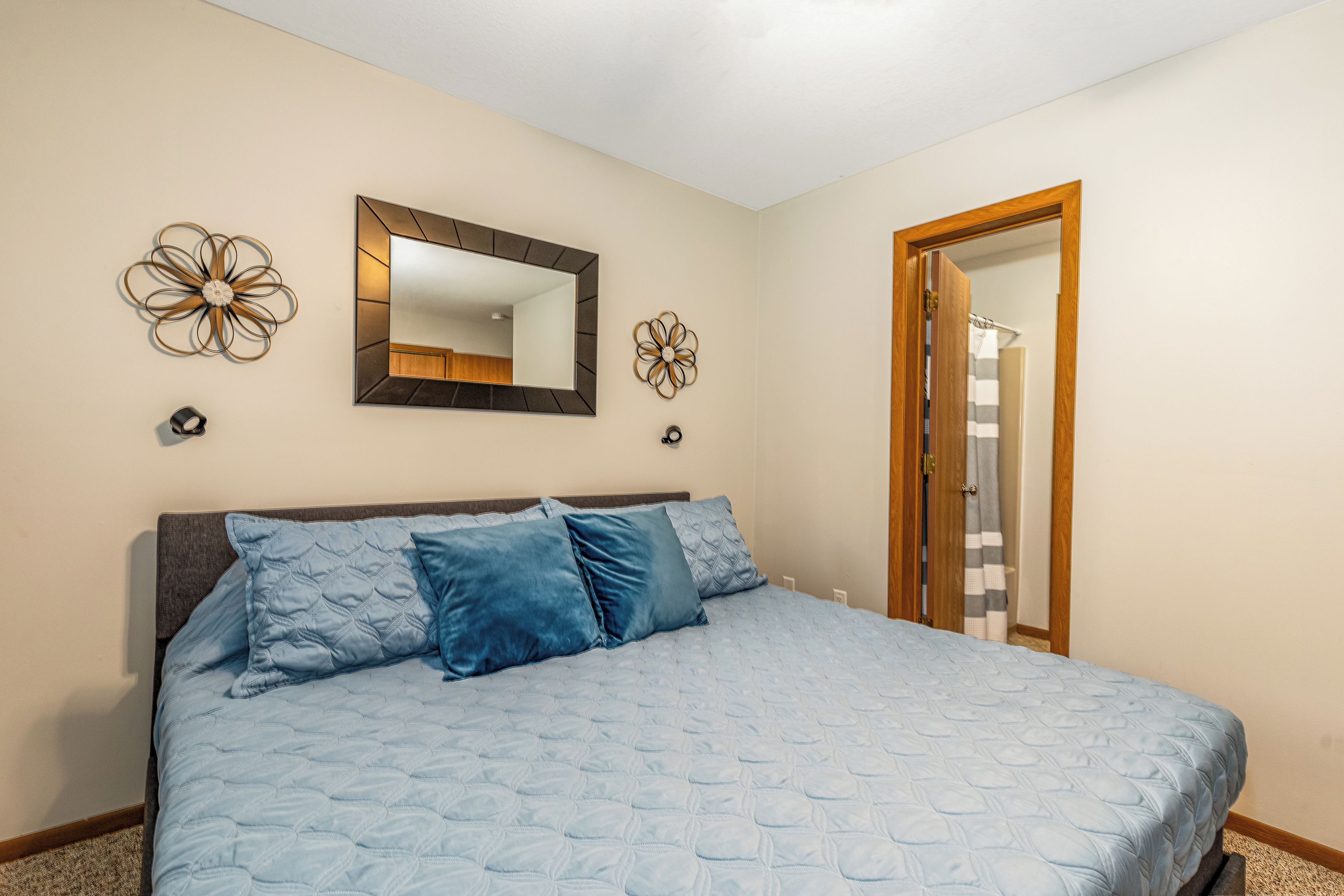 A bedroom with a bed, a mirror, and two wall decorations.