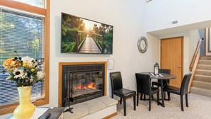 Un salon avec une cheminée, un coin repas et un escalier.