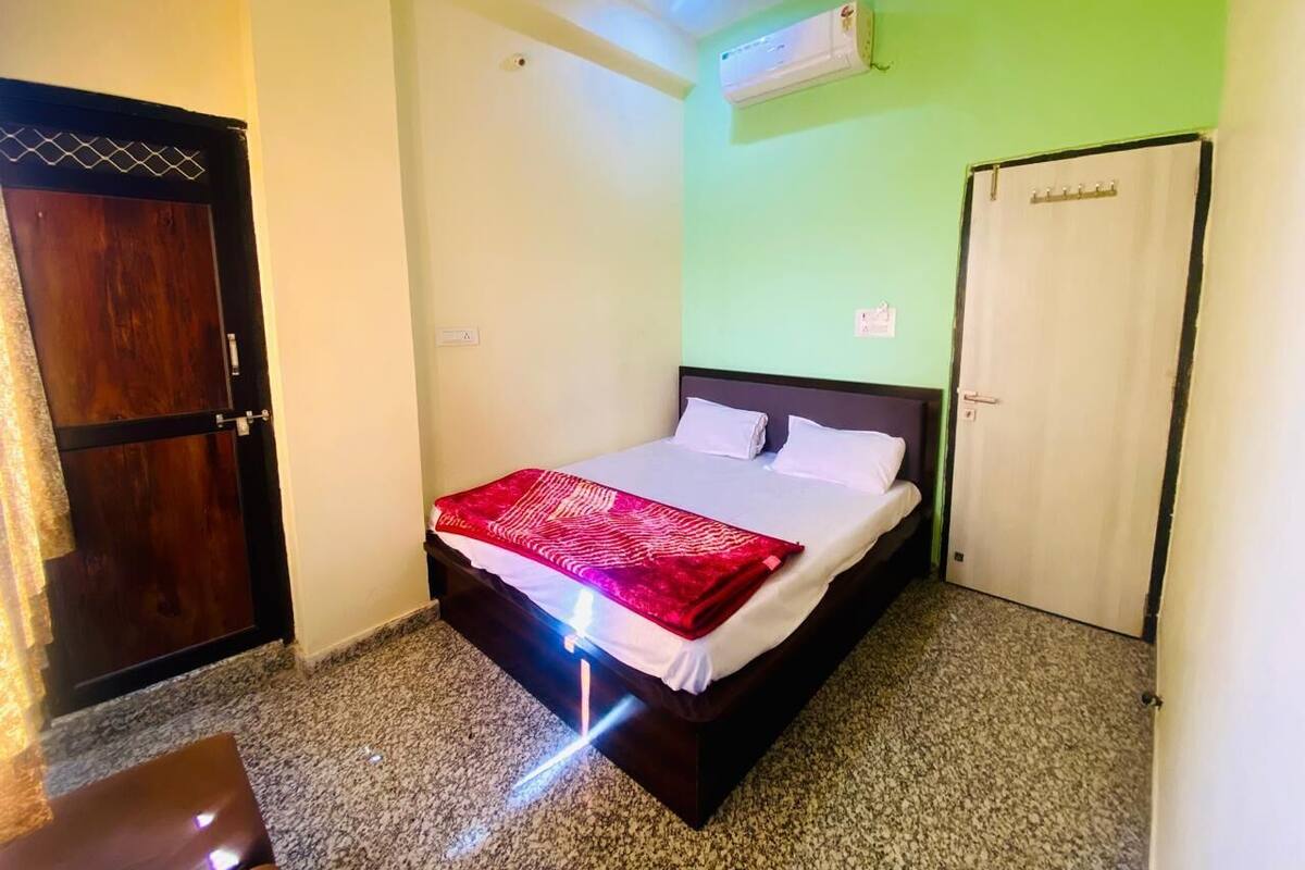 Quarto com cama, porta e unidade de ar condicionado na parede.