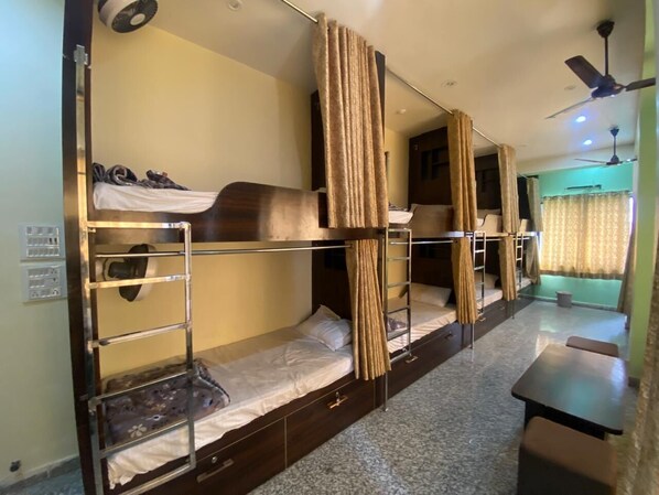 Quarto com beliche, escrivaninha e ventilador de teto.
