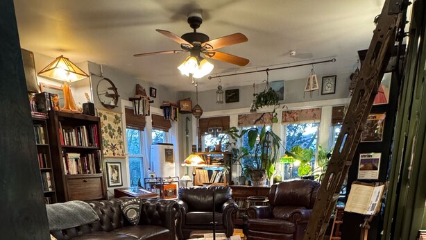 A cozy living room with leather sofas, a coffee table, and a bookshelf filled with books. - Tranquil Library near Brown Line 2 bed 1 bath vintage private unit @ Solar Lodge (Chicago)