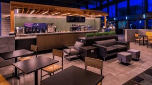Un espace intérieur moderne doté d’un bar, de différents coins salon et d’une grande fenêtre.