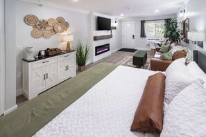 A modern bedroom with a large bed, a TV, a fireplace, a sofa, and a dining area. - Shanty Creek, Private Beach Club (Bellaire)