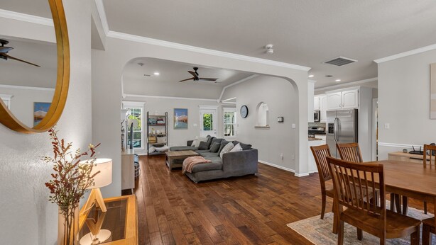 A spacious living room with hardwood flooring, a gray sectional sofa, and a dining area with wooden chairs and a table. - Jacuzzi Tub-Walk to Dining & Shopping-Garage Parking (Tulsa)
