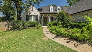 A stone house with a front porch, a covered entryway, and a well-maintained lawn. - Jacuzzi Tub-Walk to Dining & Shopping-Garage Parking (Tulsa)