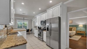 A modern kitchen with white cabinets, stainless steel appliances, and a granite countertop. - Jacuzzi Tub-Walk to Dining & Shopping-Garage Parking (Tulsa)
