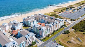 A coastal hotel with multiple buildings, a beach, and a parking lot. - New! Island Breeze/3Bd/Oceanfront/ Beach/Pool/Gym (Virginia Beach)
