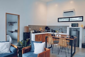A modern kitchen with a central island, dining area with chairs, and a seating area with a sofa and cushions. - Mamaya Rental Villa El Nido (El Nido)