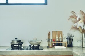 Una cocina con estufa a gas, una olla, un tazón y diversos utensilios de cocina.