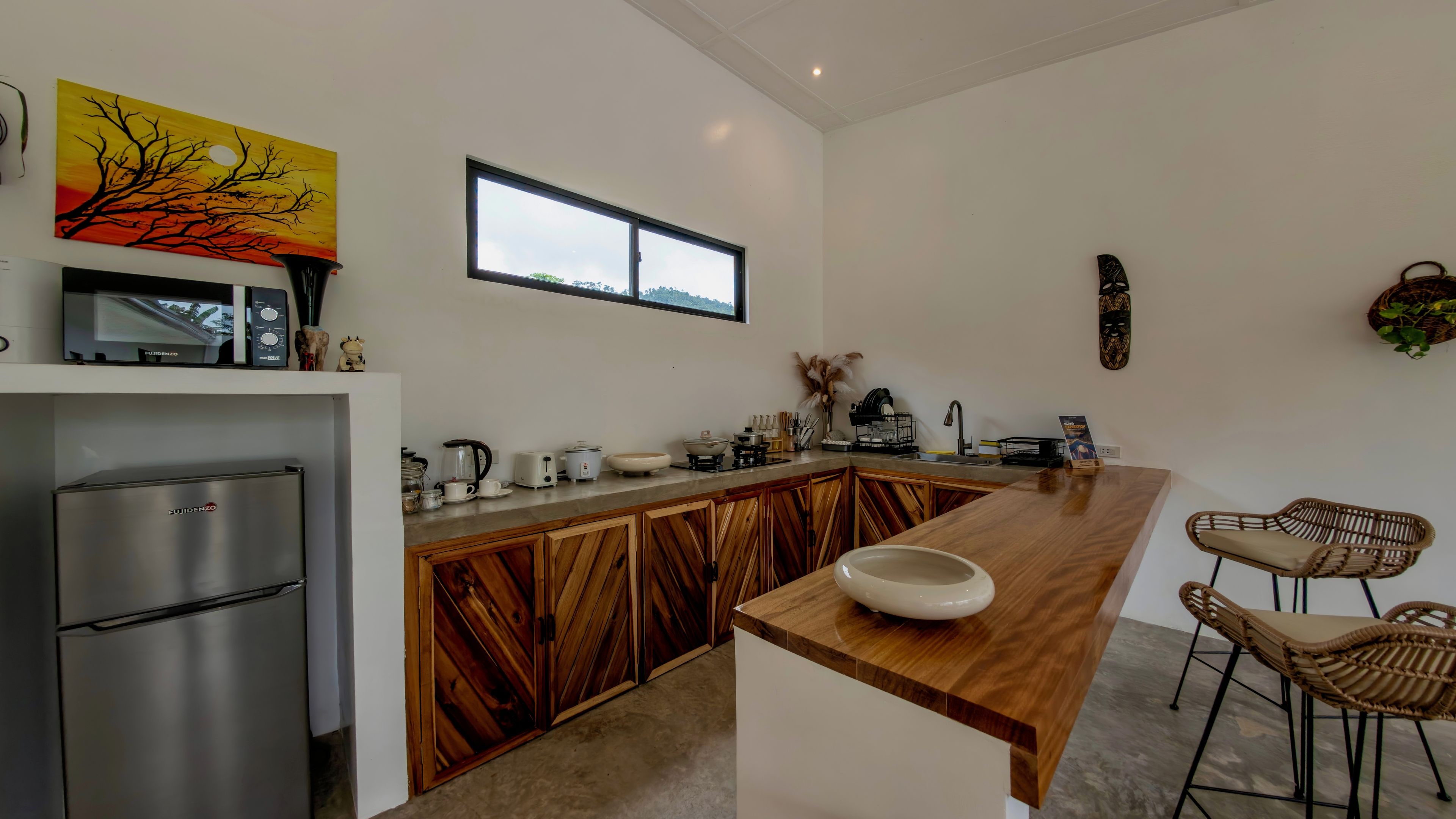 Una cocina moderna con una isla de madera, electrodomésticos de acero inoxidable y un amplio ventanal.