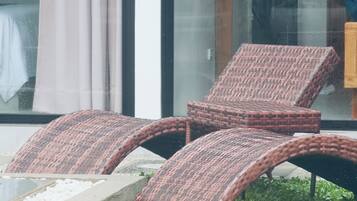 Un área de estar moderna al aire libre con sillones reclinables de mimbre.