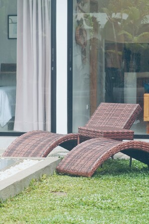 Un área de estar moderna al aire libre con sillones reclinables de mimbre.
