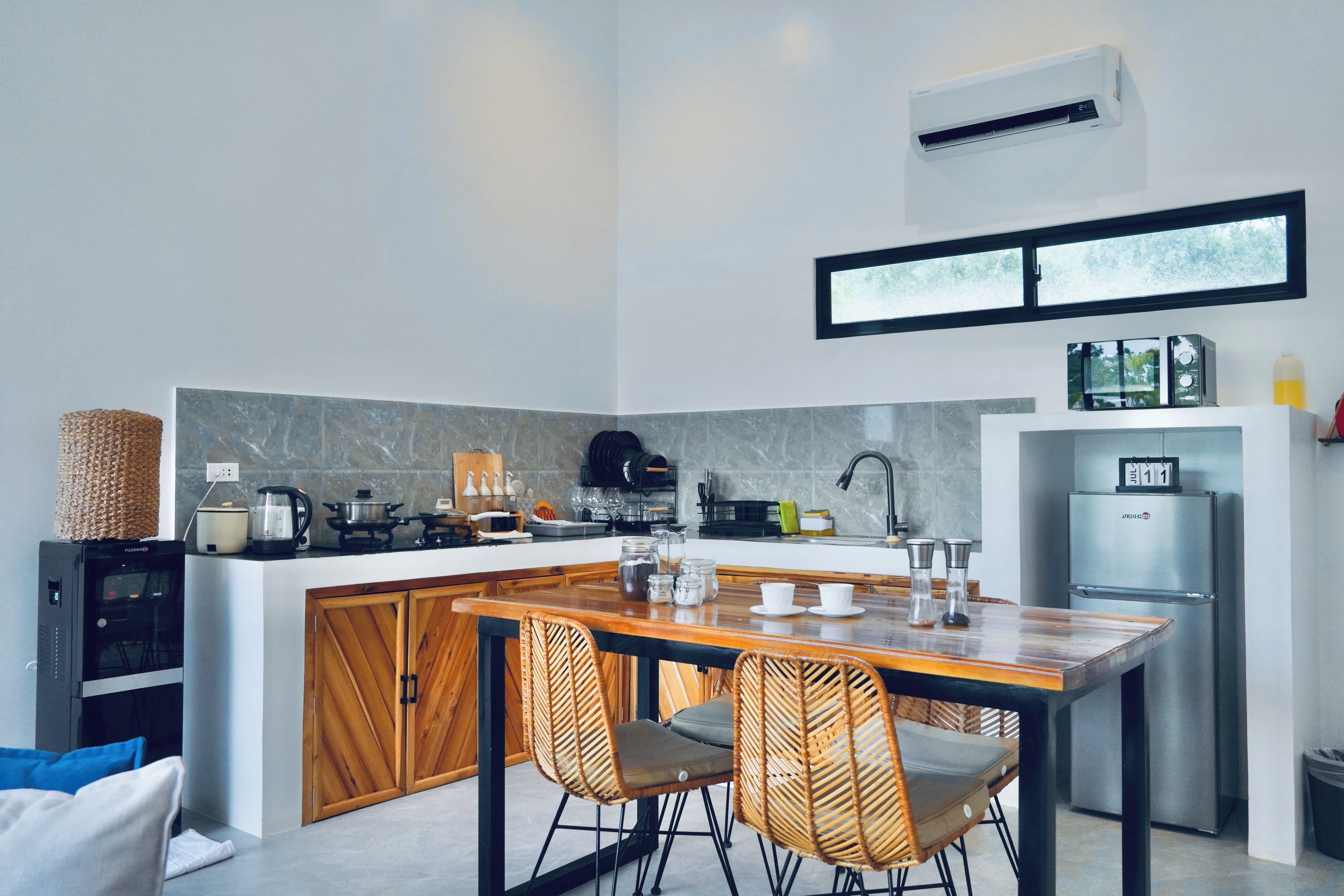 Una cocina moderna con una isla central, sillas de madera y un refrigerador empotrado.