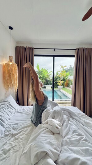 Un dormitorio con una cama grande, vistas a una piscina y cortinas.