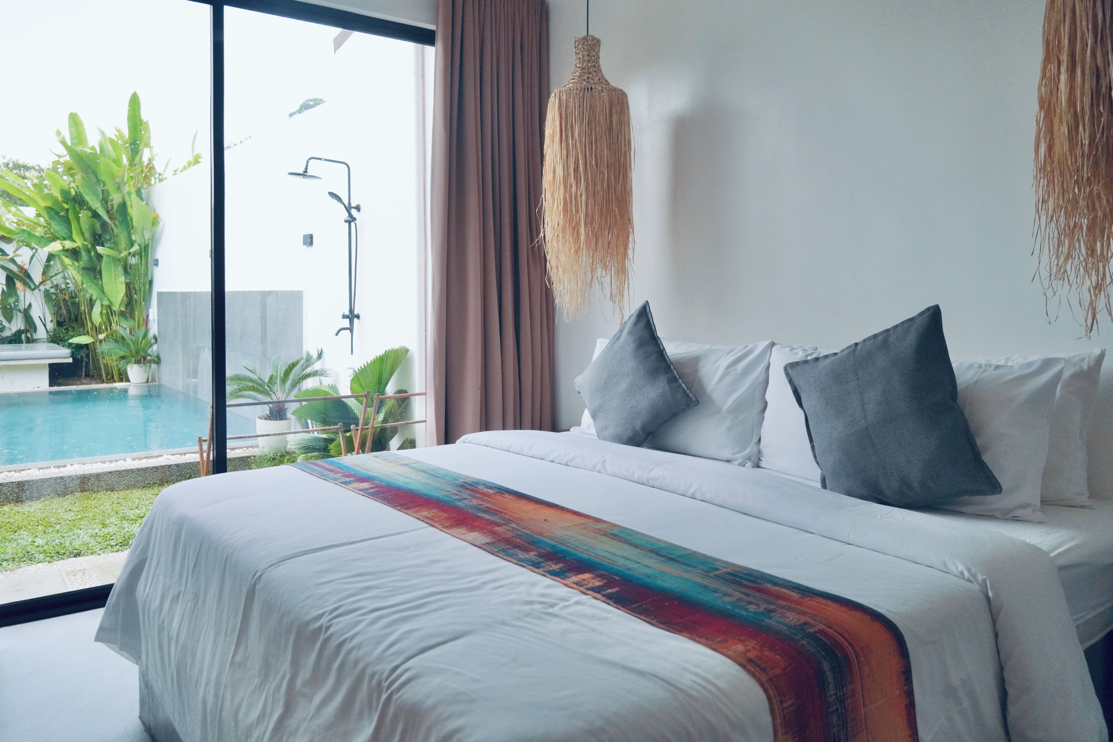 Habitación de hotel con una cama grande, vistas a una piscina y un balcón con plantas.