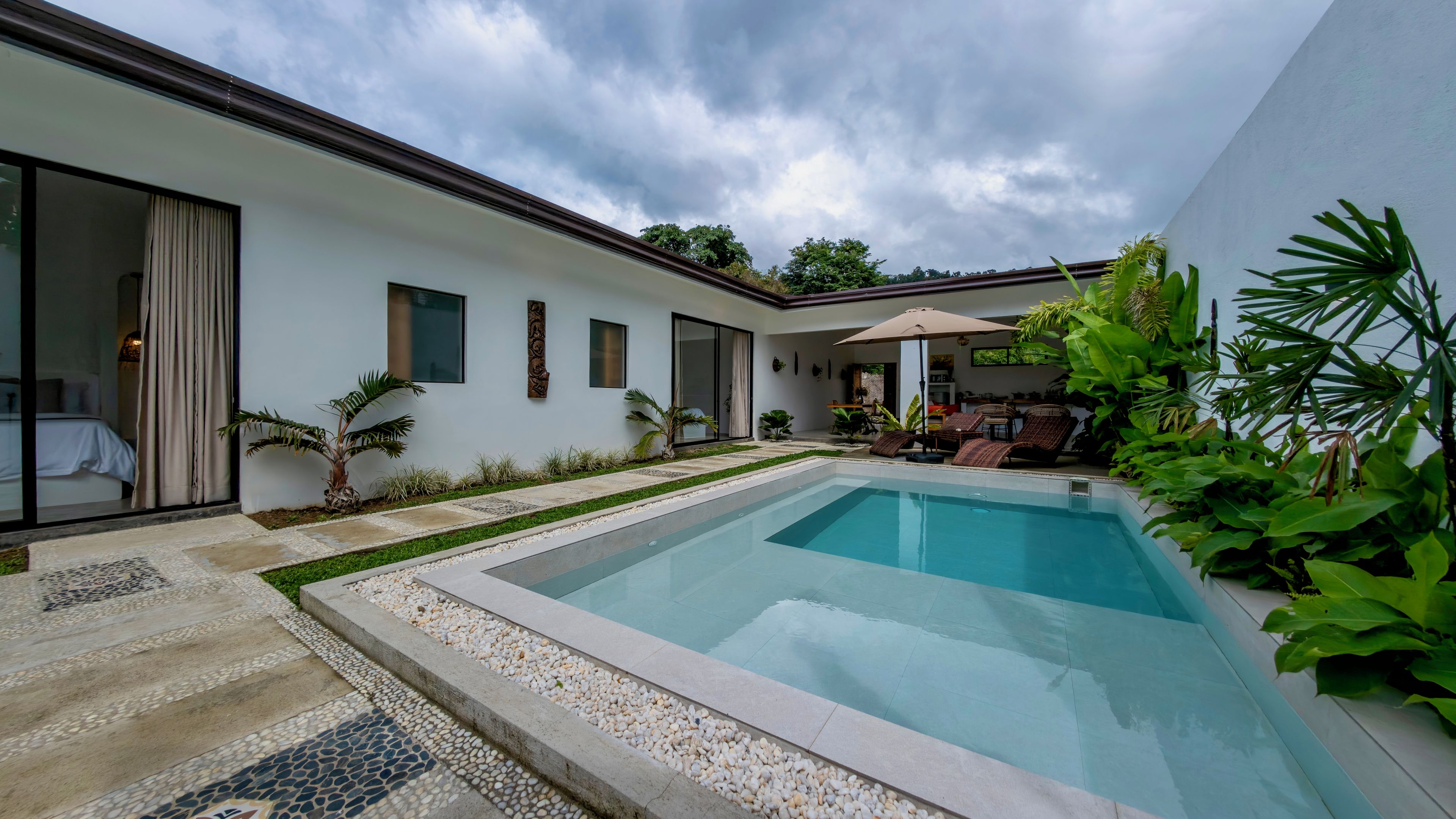 Una casa moderna con piscina, un patio amueblado y un jardín.