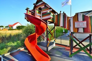 A playground with a red slide and a wooden climbing structure. - Comfortable Holiday Homes Close to the Beach (Ustronie Morskie)
