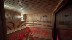Eine Sauna mit Holzwänden und -bänken, ausgestattet mit roter LED-Beleuchtung.