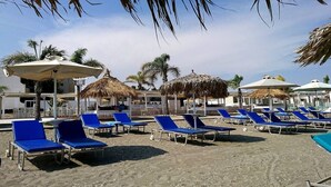 Ein Strand mit blauen Liegestühlen und Strohdächern.