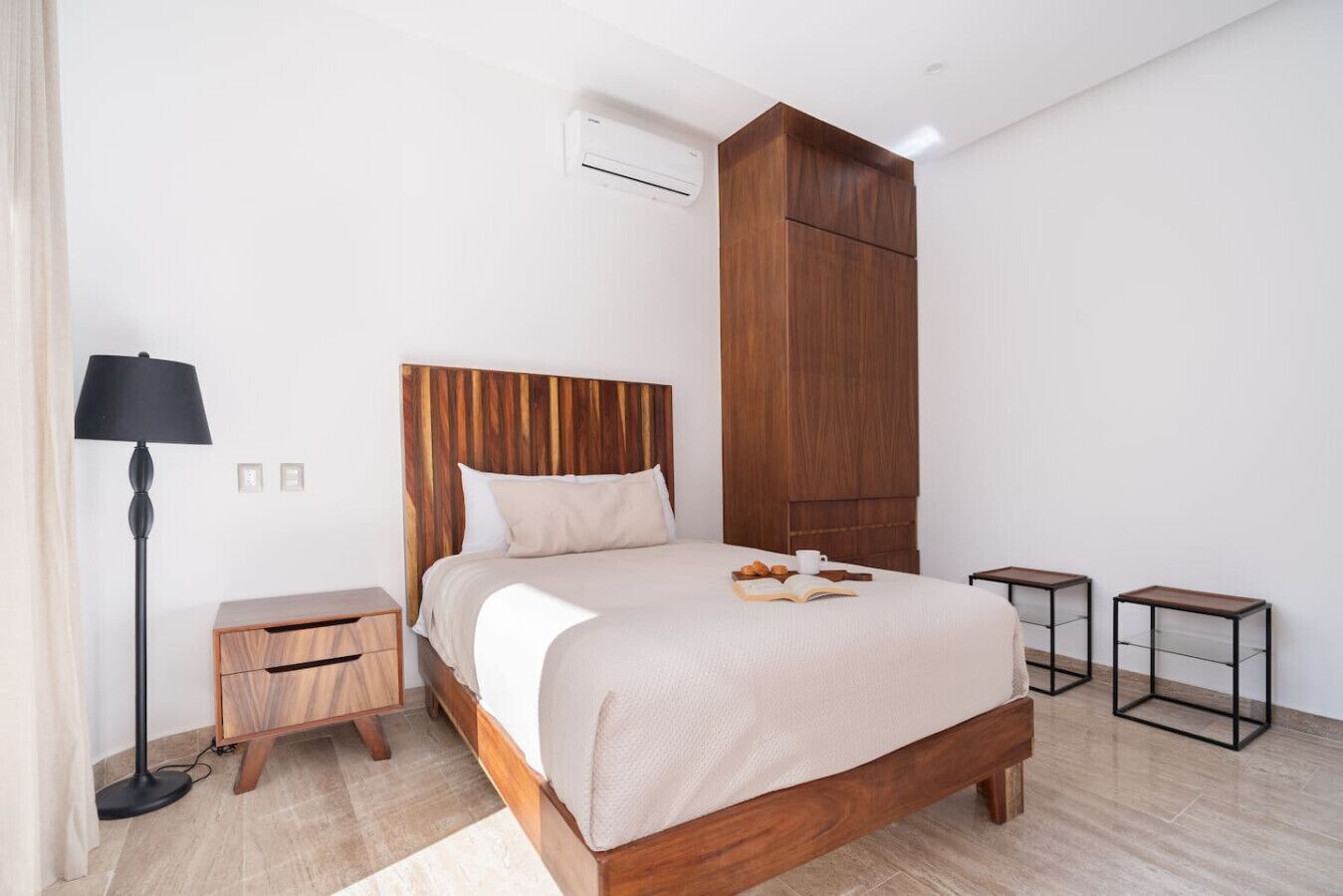 A modern bedroom with a wooden bed, bedside tables, a floor lamp, and a wardrobe.