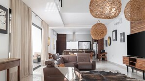 A modern living room with a sofa set, a wooden coffee table, and a television on a wooden stand. - Villa Amalia, 5 bdr w/Private Pool in Aldea  Zama (Tulum)