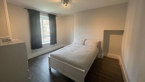 A bedroom with a bed, a window with curtains, a radiator, and a white wardrobe. - Vauxhall Central Room 3 (Greater London)