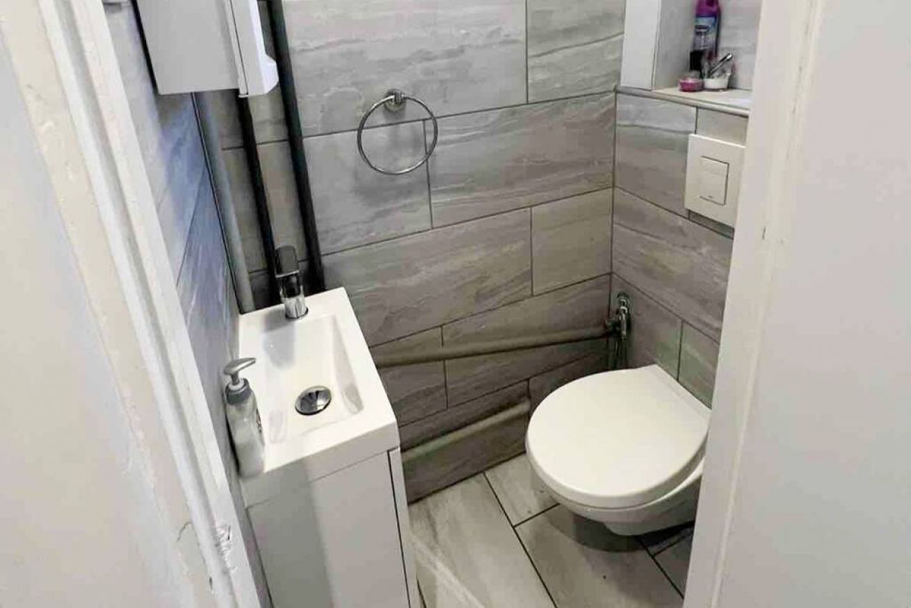 A small bathroom with a toilet, sink, and a towel rack.