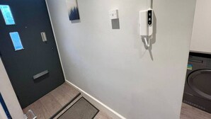 Käytävä, jossa on ovi, seinään asennettu valokytkin ja seinään asennettu termostaatti.
