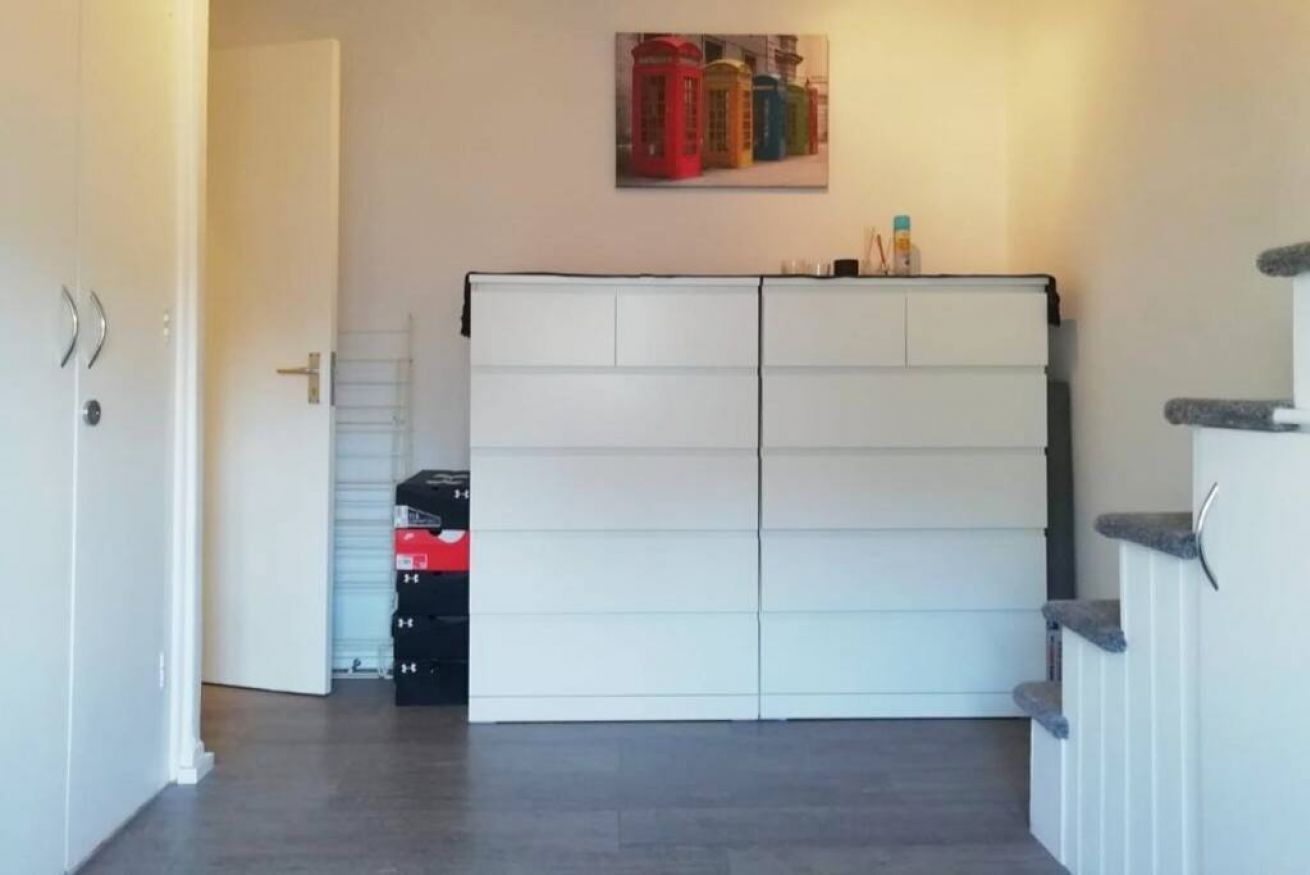 Une pièce avec une armoire blanche, une porte et un escalier.