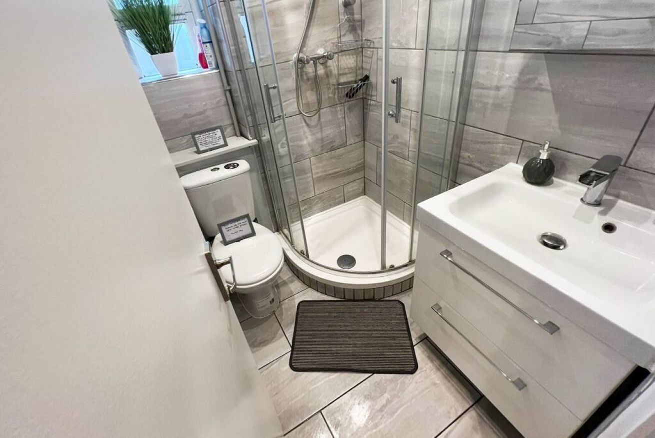 A modern bathroom with a glass-enclosed shower, a white sink, and a toilet.