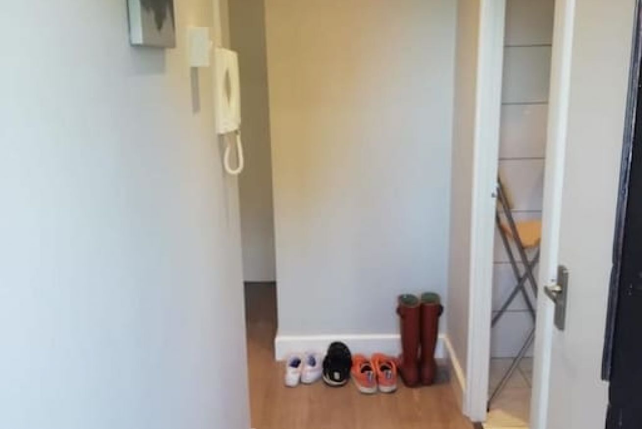 A hallway with a telephone, a set of shoes, and a door leading to another room.