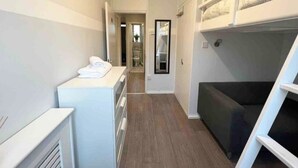 A narrow hallway with a bunk bed, a small kitchenette, and a door leading to a bathroom. - Vauxhall Central Room 2 (Greater London)