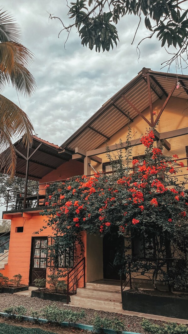 Um edifício de dois andares com fachada vermelha, uma varanda e uma escadaria que leva à entrada.