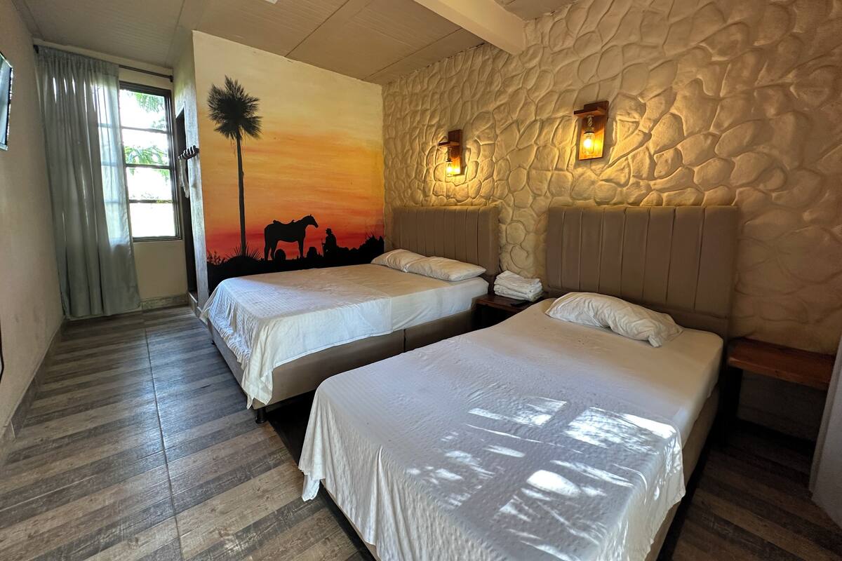 A room with two beds, a stone wall, and a sunset mural.