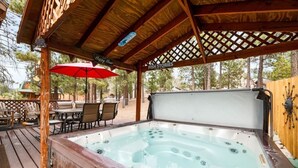 An outdoor hot tub area with a wooden deck, lounge chairs, and a red umbrella. - Lakeside Cottage, Charming 3-BDRM Retreat W Hottub (Big Bear Lake)
