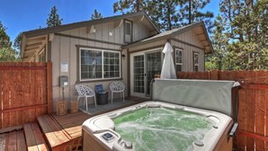 Eine Hütte mit Whirlpool, einer Holzterrasse und einem eingezäunten Patio.