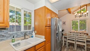 Eine Küche mit Holzschränken, einem Edelstahlkühlschrank, einer Spüle und einem Essbereich mit Tisch und Stühlen.